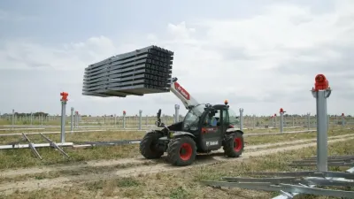Teleskopický manipulátor Bobcat přepravuje konstrukci na stavbě