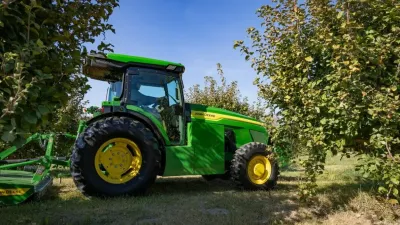Zelený traktor John Deere v sadu