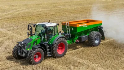 Zelený traktor s rozmetadlem hnojiva na poli
