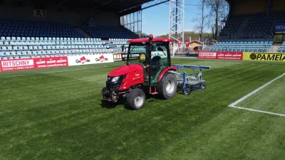 Červený traktor TYM na fotbalovém trávníku