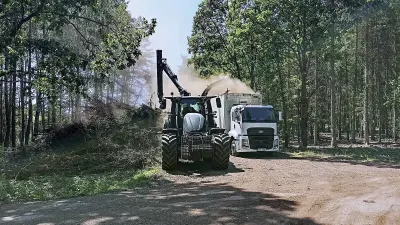 Traktor s nakládací rukou a nákladní vůz při práci v lese
