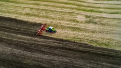 Červený traktor s diskovým nářadím na poli z ptačí perspektivy