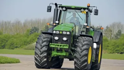 Zelený traktor John Deere 8430 při jízdě po cestě