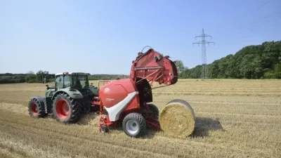 Traktor s červeným lisem Lely při lisování balíku