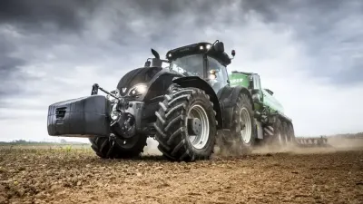 Tmavý traktor Valtra pracuje na poli