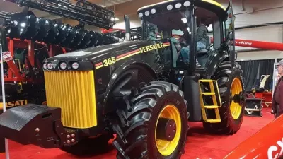 Černý traktor Versatile 365 se žlutými koly na výstavě.