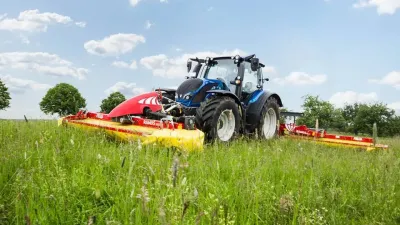 Modrý traktor s žacími stroji Fella na louce