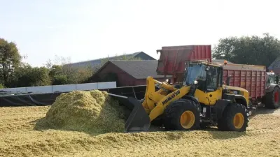Žlutý kolový nakladač Komatsu při práci se siláží