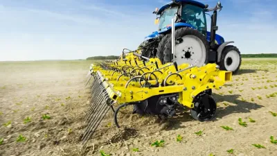 Modrý traktor táhne žlutý stroj BEDNAR na poli