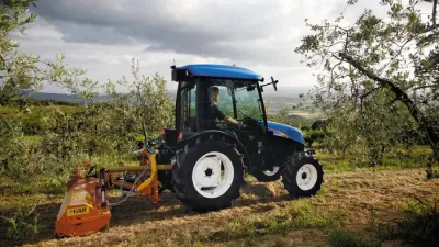 Modrý traktor New Holland v sadu