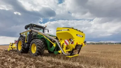 Zelený traktor se žlutým strojem Bednar na poli