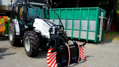 Bílý traktor s čelním zařízením a zelenou nástavbou na výstavě Agrokomplex