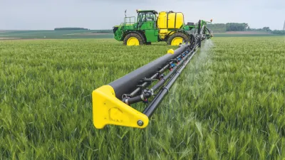 Zelený samojízdný postřikovač John Deere v obilí
