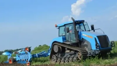 Modrý pásový traktor Agromash s pluhem