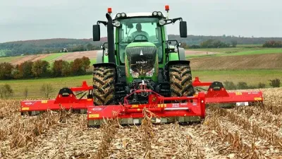 Zelený traktor s červeným mulčovačem Kuhn na poli