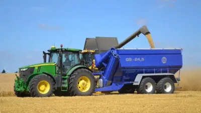 Traktor John Deere s modrým překládacím vozem při sklizni