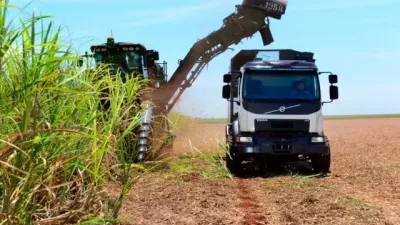 Samojízdný sklízeč cukrové třtiny plní nákladní automobil Volvo
