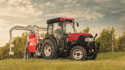 Červený traktor Case IH s postřikovačem ve vinici