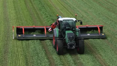Traktor s širokým shrnovačem Kuhn na louce