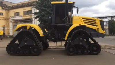 Žlutý pásový traktor Kirovets na dvoře