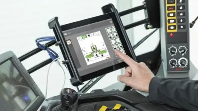 Obsluha ovládá zemědělský stroj pomocí tabletu v kabině