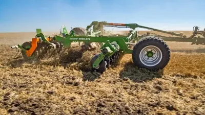 Zelený diskový podmítač Amazone Catros při práci na poli