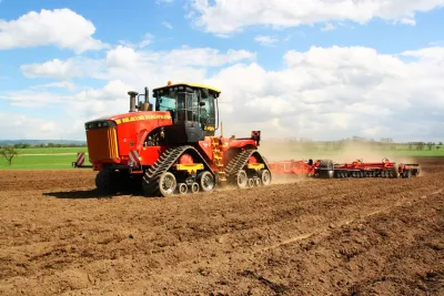 Červený pásový traktor Versatile 610 DT při práci na poli