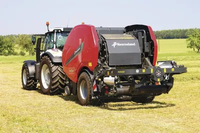Traktor s červeným lisem a ovíječkou Kverneland FastBale na louce