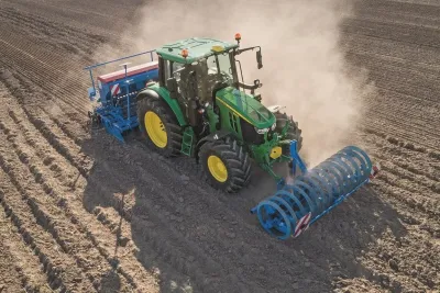 Traktor John Deere 6M se secím strojem na poli