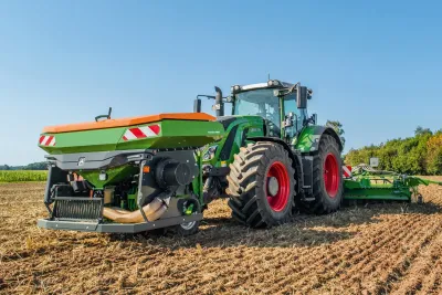 Traktor Fendt se zeleným čelním zásobníkem Amazone FTender na poli