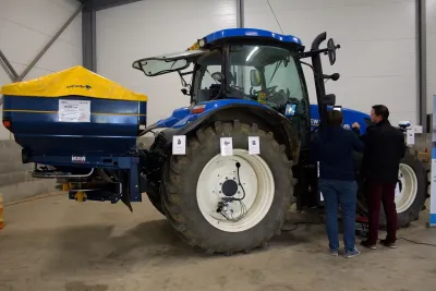 Modrý traktor New Holland s rozmetadlem při technickém testování