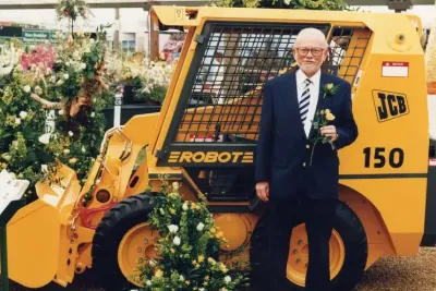 Žlutý smykem řízený nakladač JCB Robot u záhonu květin