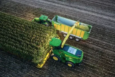 Řezačka John Deere a traktor synchronizovaně při sklizni kukuřice