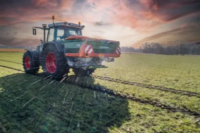 Traktor s neseným rozmetadlem Amazone při práci na poli