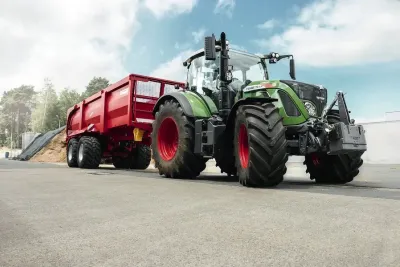 Traktor Fendt se zapřaženým červeným přívěsem