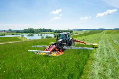 Traktor s žacím strojem Pöttinger Sensosafe na louce.