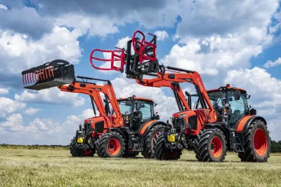 Dva oranžové traktory Kubota s různým příslušenstvím čelních nakladačů.