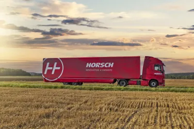 Červený nákladní vůz s logem Horsch projíždí krajinou.