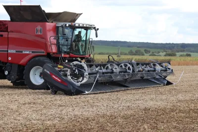 Červená sklízecí mlátička Case IH s žací lištou MacDon FD2 na poli.