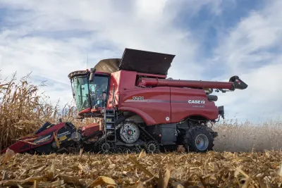 Červený pásový kombajn Case IH Axial-Flow 7250 sklízí kukuřici.
