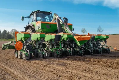Přesný secí stroj Amazone Precea zapojený za traktorem na poli.