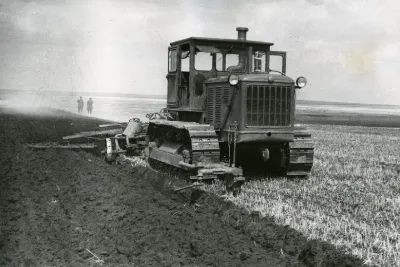 Historický sovětský pásový traktor při orbě pole.