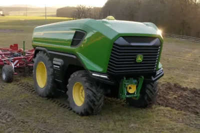 Zelený autonomní traktor John Deere s nářadím na poli