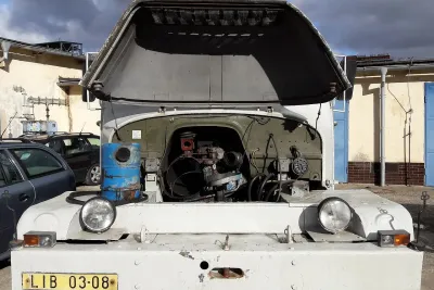 Otevřená kapota vozu Praga V3S. Motor má demontovaný ventilátor a čistič vzduchu. Hrnec čističe je na blatníku.