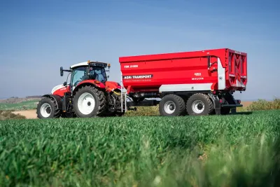 Červený traktor s návěsem Agri Transport TDK 21000 na poli