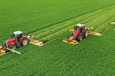Traktory se žací technikou Pöttinger sečou zelenou louku.