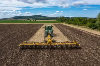 Traktor s širokým podmítačem BEDNAR SWIFTERDISC na poli.