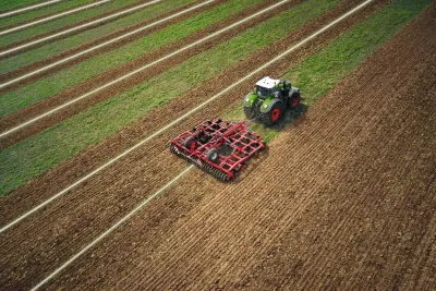 Traktor Fendt s červeným kypřičem při práci na poli.