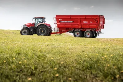 Červený dvounápravový návěs AGRI TRANSPORT za traktorem.