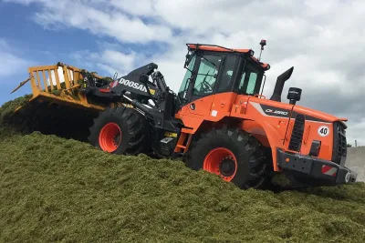 Oranžový kolový nakladač Doosan při práci se siláží.